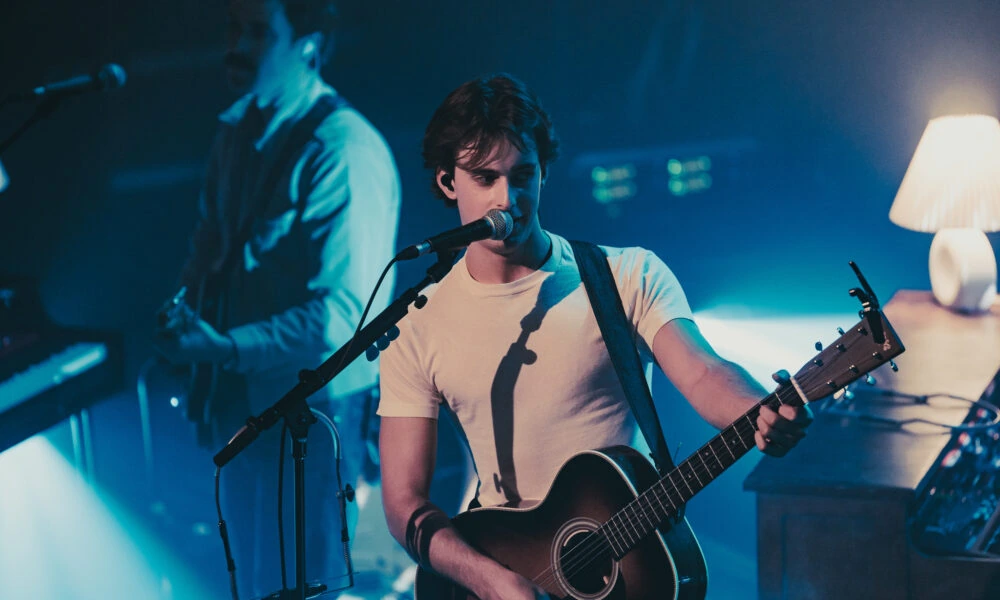Aiden Kroll performing with a guitar on stage